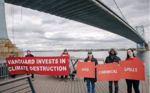 Activists hold banners saying "Vanguard invests in climate destruction and chemical spills"