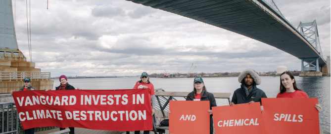 Activists hold banners saying "Vanguard invests in climate destruction and chemical spills"