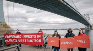 Six people holding signs that say "Vanguard invests in climate destruction and chemical spills."